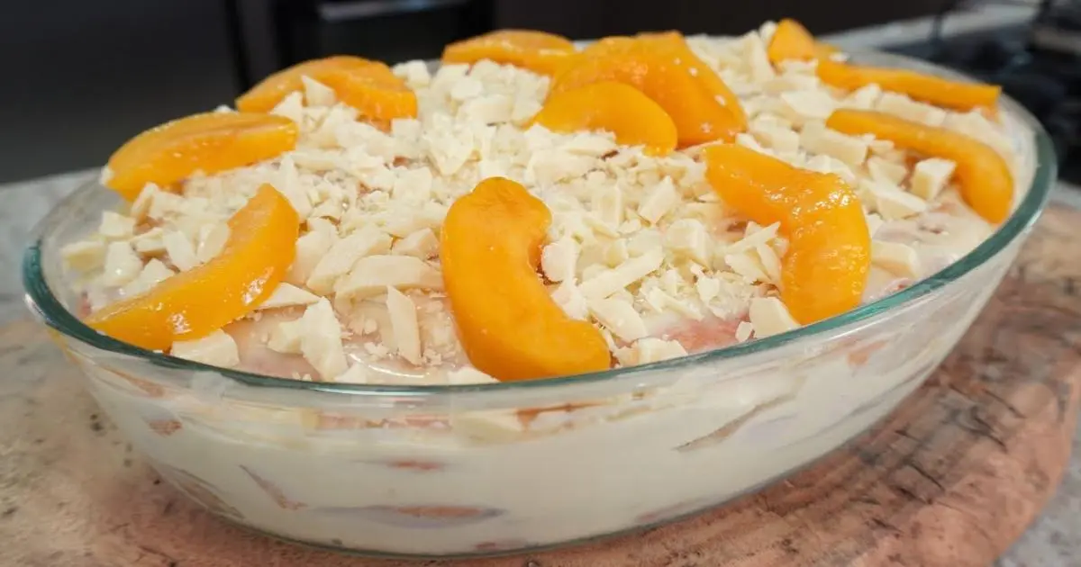 Sobremesa gelada de pêssego com camadas cremosas e toque de chocolate branco....